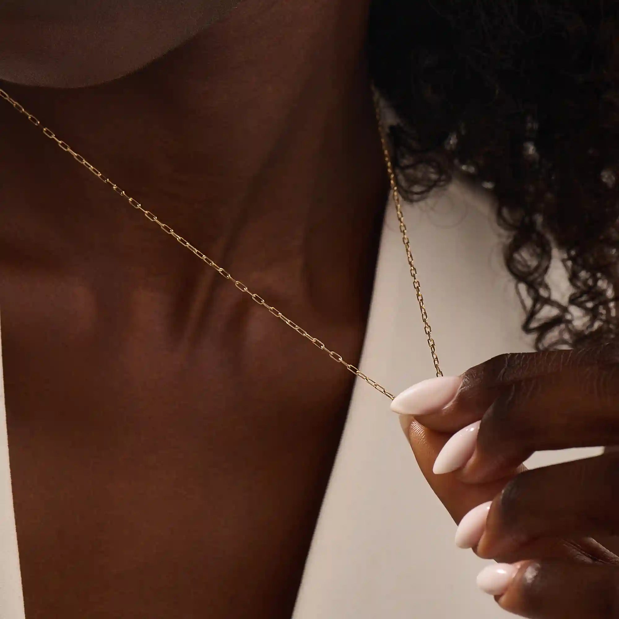 Woman wearing a 14k solid gold slim link chain necklace. Minimal and easy-to-style piece for everyday outfits. Perfect as a base for layering or simple looks.