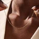 Woman wearing a 14k solid gold slim link chain necklace. Minimal and easy-to-style piece for everyday outfits. Perfect as a base for layering or simple looks.