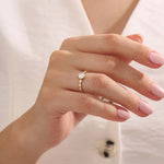 Woman wearing a 14k solid gold solitaire engagement ring with a bezel-set moissanite and fine band details. Elegant and minimal with a unique touch. Ideal for everyday wear and special moments.