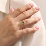 Woman wearing a 14k solid gold spiral ring with an emerald centerpiece. Eye-catching and modern with a touch of color. Ideal for everyday wear or special occasions.