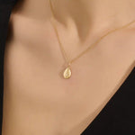 Woman wearing a 14k solid gold teardrop necklace with a tiny moissanite centerpiece. Elegant and dainty gold pendant for daily style. Subtle sparkle for modern looks.