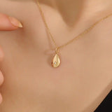 Woman wearing a 14k solid gold teardrop necklace with a tiny moissanite centerpiece. Elegant and dainty gold pendant for daily style. Subtle sparkle for modern looks.