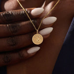 Woman wearing a 14k solid gold water lily pendant necklace with a delicate moissanite accent. Nature-inspired fine jewelry styled for everyday wear. Elegant and minimalist gold necklace for women.