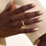 Close-up of a woman's hand wearing a 14k solid yellow gold ivy leaf wedding band. The detailed leaf motifs and smooth polished interior reflect a blend of natural inspiration and artisan craftsmanship, making it a distinctive and elegant choice for daily wear or special occasions.
