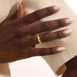 Close-up of a woman's hand wearing a 14k solid yellow gold ivy leaf wedding band. The detailed leaf motifs and smooth polished interior reflect a blend of natural inspiration and artisan craftsmanship, making it a distinctive and elegant choice for daily wear or special occasions.
