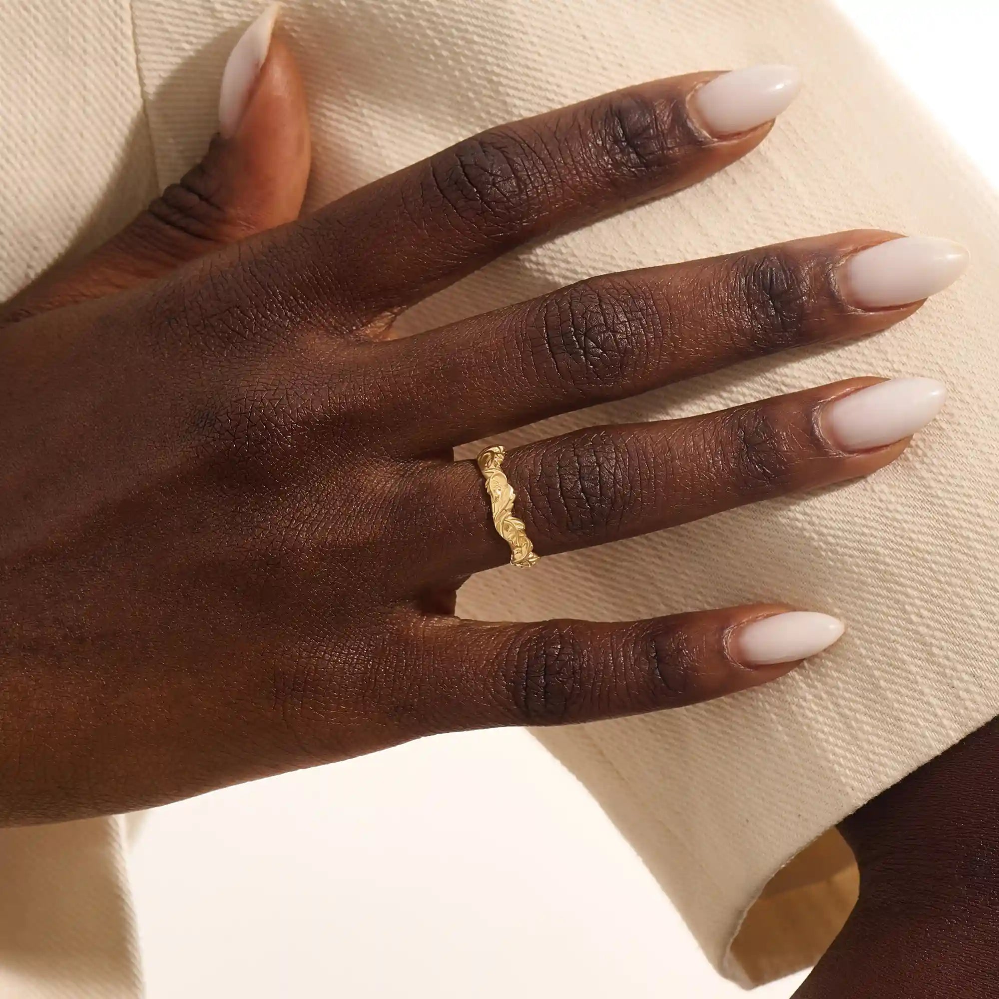 Close-up of a woman's hand wearing a 14k solid yellow gold ivy leaf wedding band. The detailed leaf motifs and smooth polished interior reflect a blend of natural inspiration and artisan craftsmanship, making it a distinctive and elegant choice for daily wear or special occasions.
