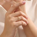 Woman wearing a 14k solid yellow gold stacking wedding ring featuring marquise-inspired sections with round brilliant cut moissanite stones on her ring finger