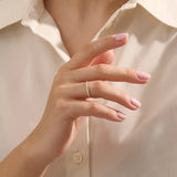 Woman wearing a 14k solid yellow gold stacking wedding ring featuring marquise-inspired sections with round brilliant cut moissanite stones on her ring finger