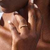 Woman wearing a 14k solid yellow gold stacking wedding ring featuring marquise-inspired sections with round brilliant cut moissanite stones on her ring finger