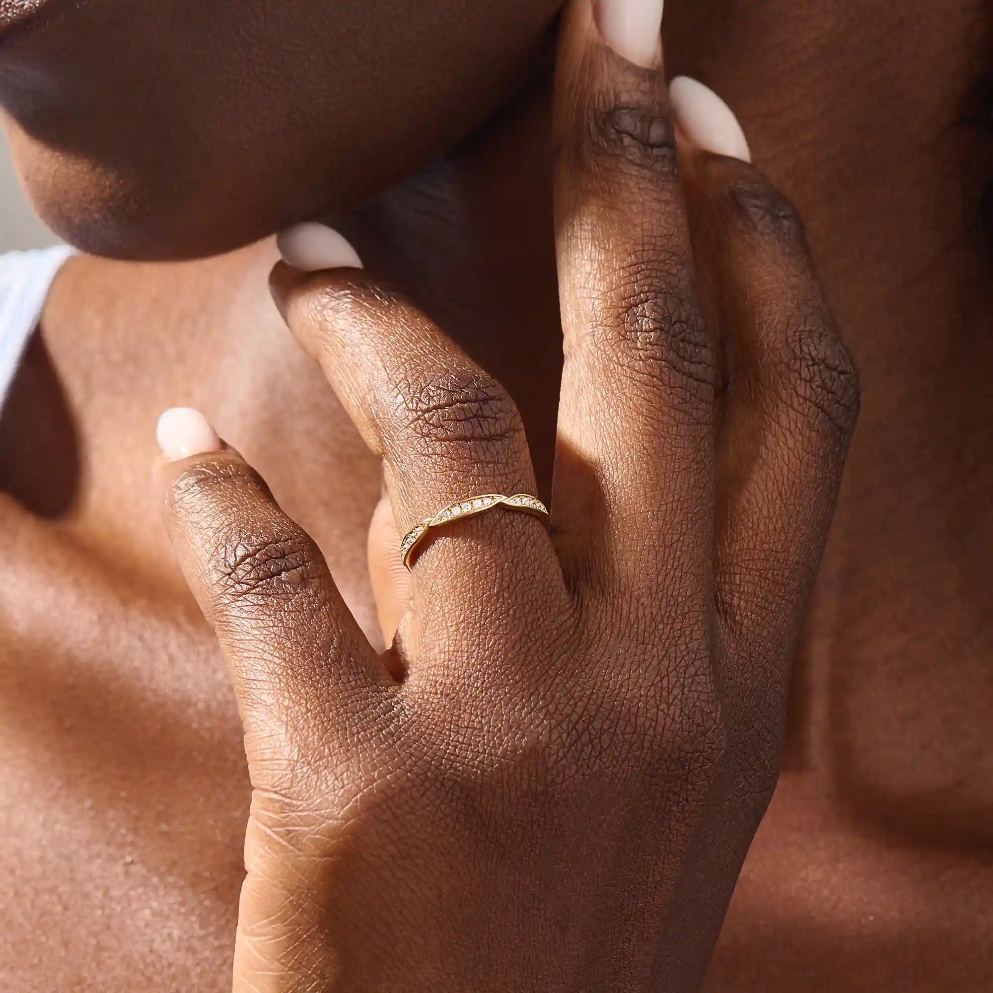 Woman wearing a 14k solid yellow gold stacking wedding ring featuring marquise-inspired sections with round brilliant cut moissanite stones on her ring finger