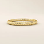 Angled view of a 14k yellow gold rope bangle highlighting its textured rope twists and elegant rounded silhouette.
