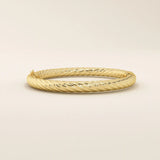 Angled view of a 14k yellow gold rope bangle highlighting its textured rope twists and elegant rounded silhouette.
