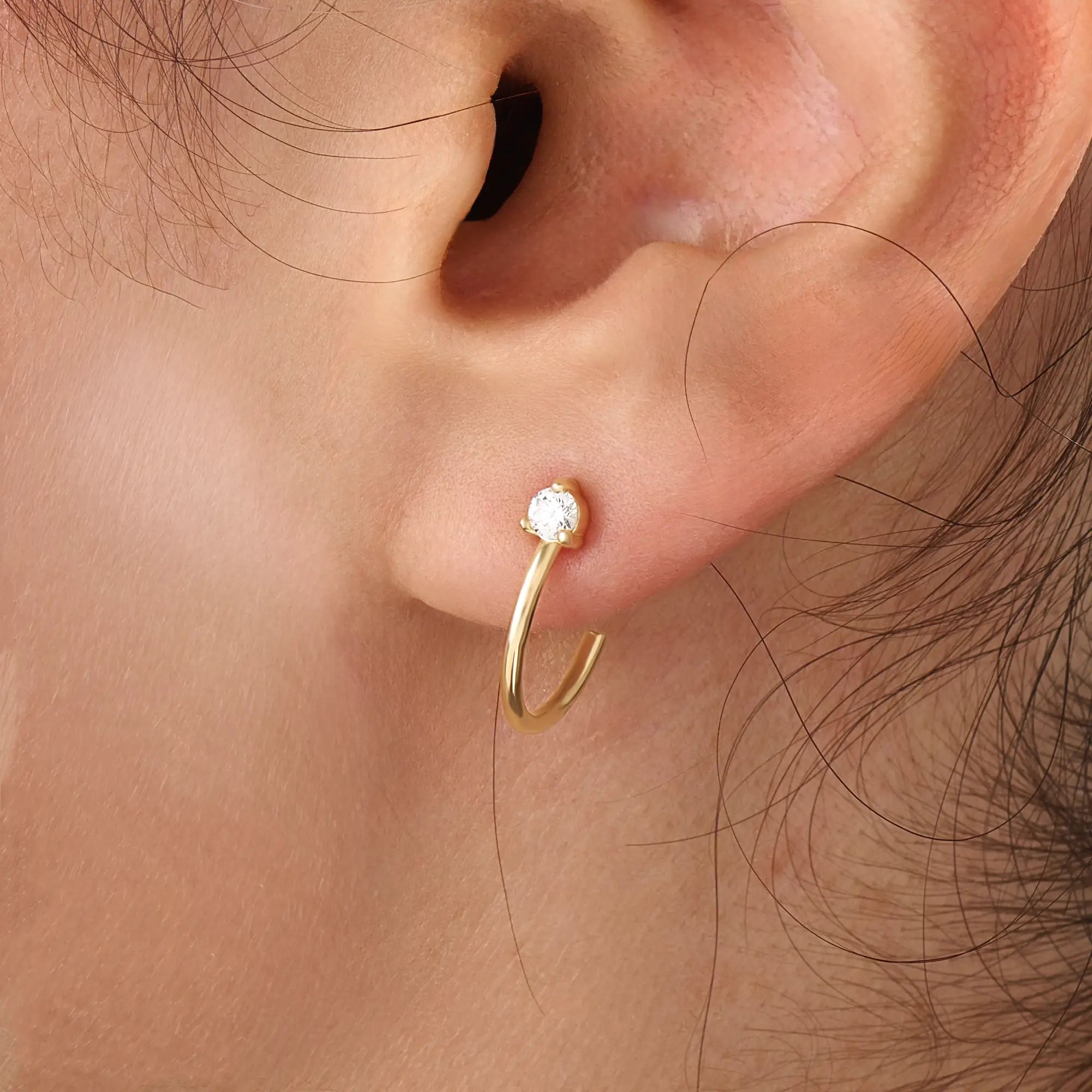 Model wearing 14k gold vermeil solo hoop earrings showcasing a single sparkling cubic zirconia, perfect for an understated yet sophisticated everyday look.
