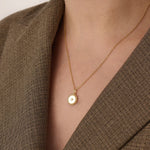 Model wearing a 14k gold vermeil beaded coin necklace featuring a gleaming pendant with a star-set cubic zirconia and ornate beaded border for a touch of everyday luxury.
