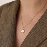 Model wearing a 14k gold vermeil beaded coin necklace featuring a gleaming pendant with a star-set cubic zirconia and ornate beaded border for a touch of everyday luxury.
