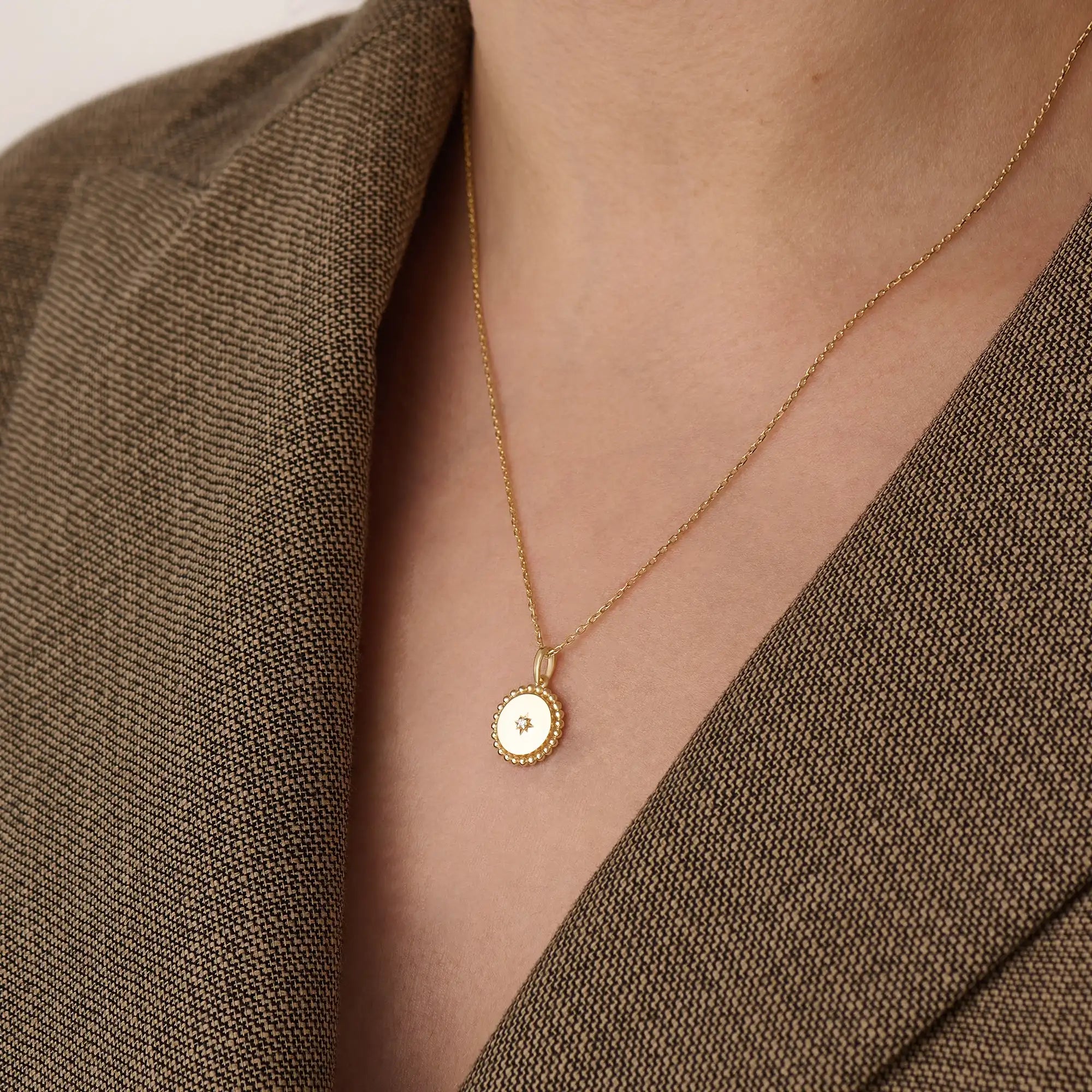 Model wearing a 14k gold vermeil beaded coin necklace featuring a gleaming pendant with a star-set cubic zirconia and ornate beaded border for a touch of everyday luxury.
