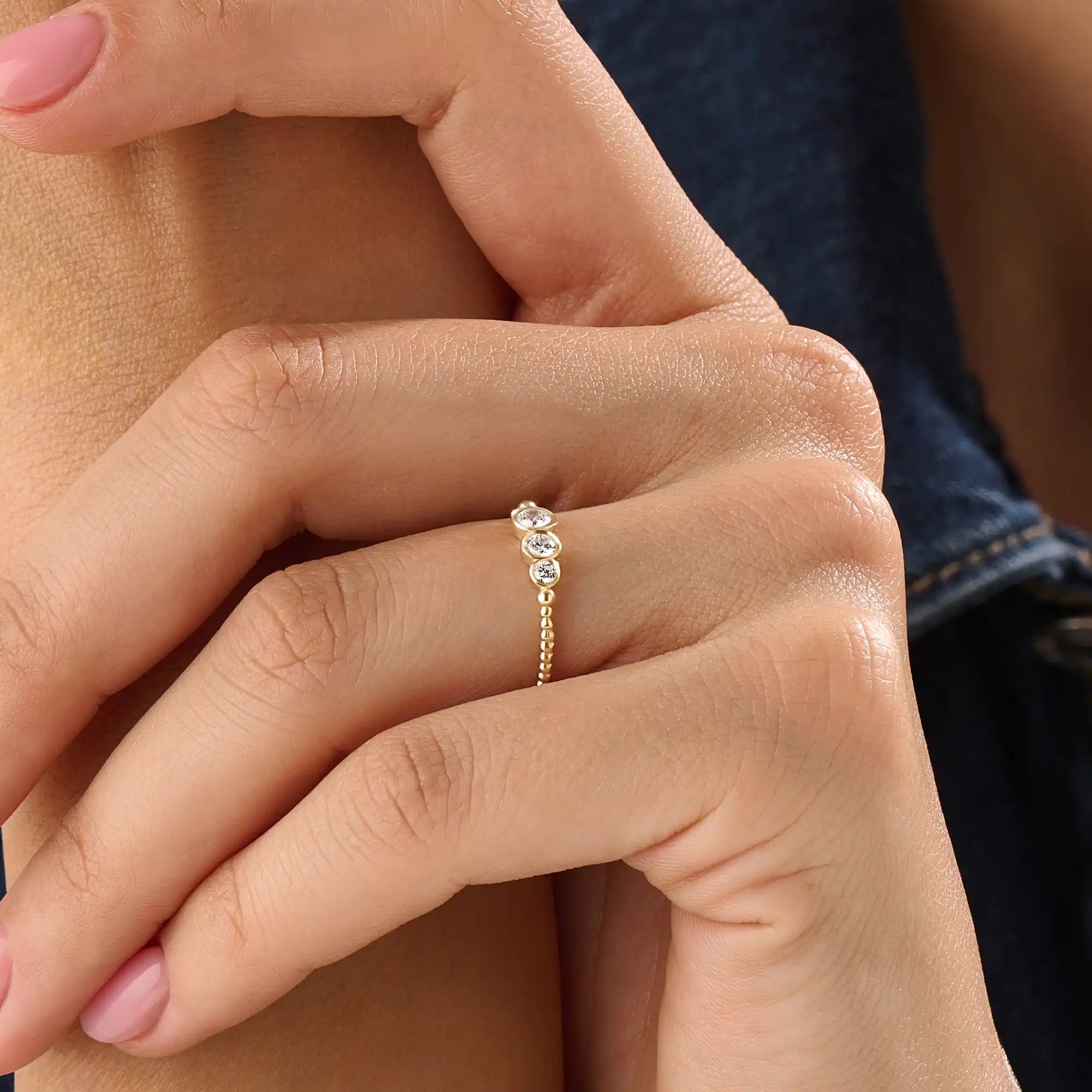 Model wearing a 14k gold vermeil beaded trio ring featuring three round cubic zirconia stones, adding a subtle sparkle to a modern everyday look.
