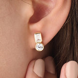 Model wearing 14k gold vermeil toi et moi stud earrings featuring a duo of emerald and round-cut stones, exuding modern sophistication with a classic touch.
