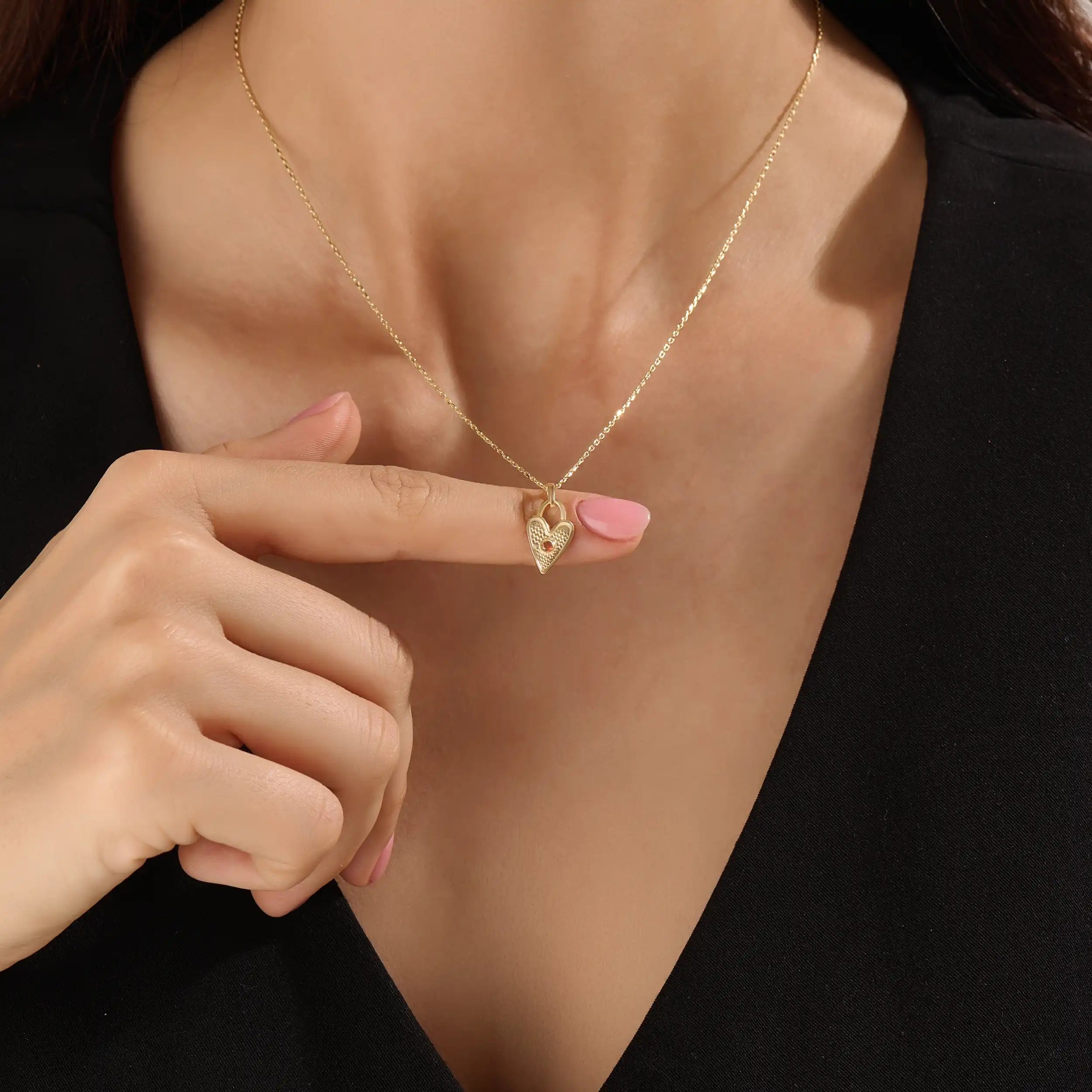 Model wearing a 14k gold vermeil birthstone heart necklace featuring a unique heart lock pendant with a colored gemstone accent for a sentimental, stylish statement.
