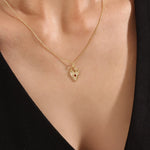 Model wearing a 14k gold vermeil birthstone heart necklace featuring a unique heart lock pendant with a colored gemstone accent for a sentimental, stylish statement.
