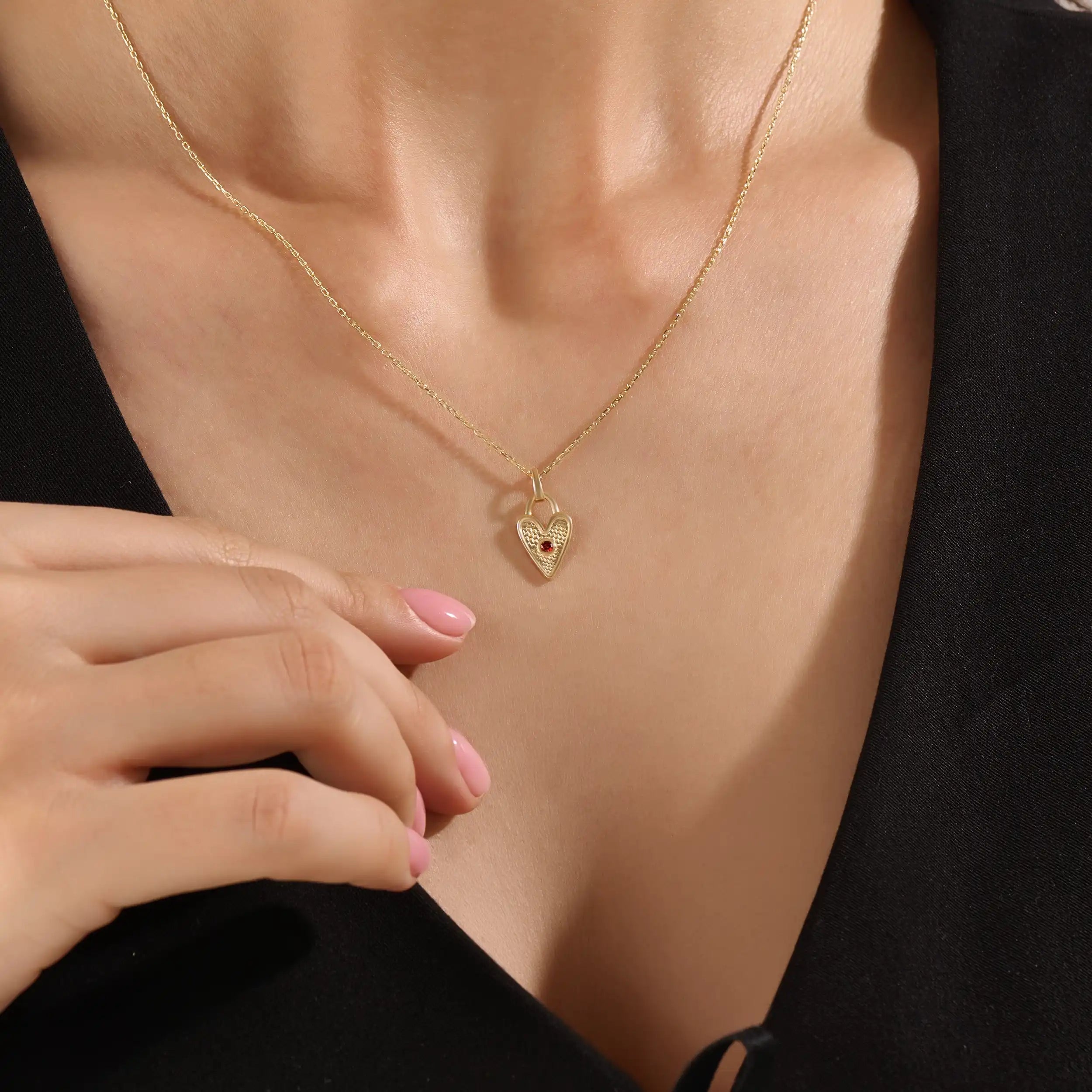 Model wearing a 14k gold vermeil birthstone heart necklace featuring a unique heart lock pendant with a colored gemstone accent for a sentimental, stylish statement.
