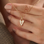 Model wearing a 14k gold vermeil birthstone heart necklace featuring a unique heart lock pendant with a colored gemstone accent for a sentimental, stylish statement.
