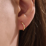 Model wearing 14k gold vermeil bone hoop earrings that highlight the sculpted, biomorphic design — a perfect mix of artistry and sophistication.
