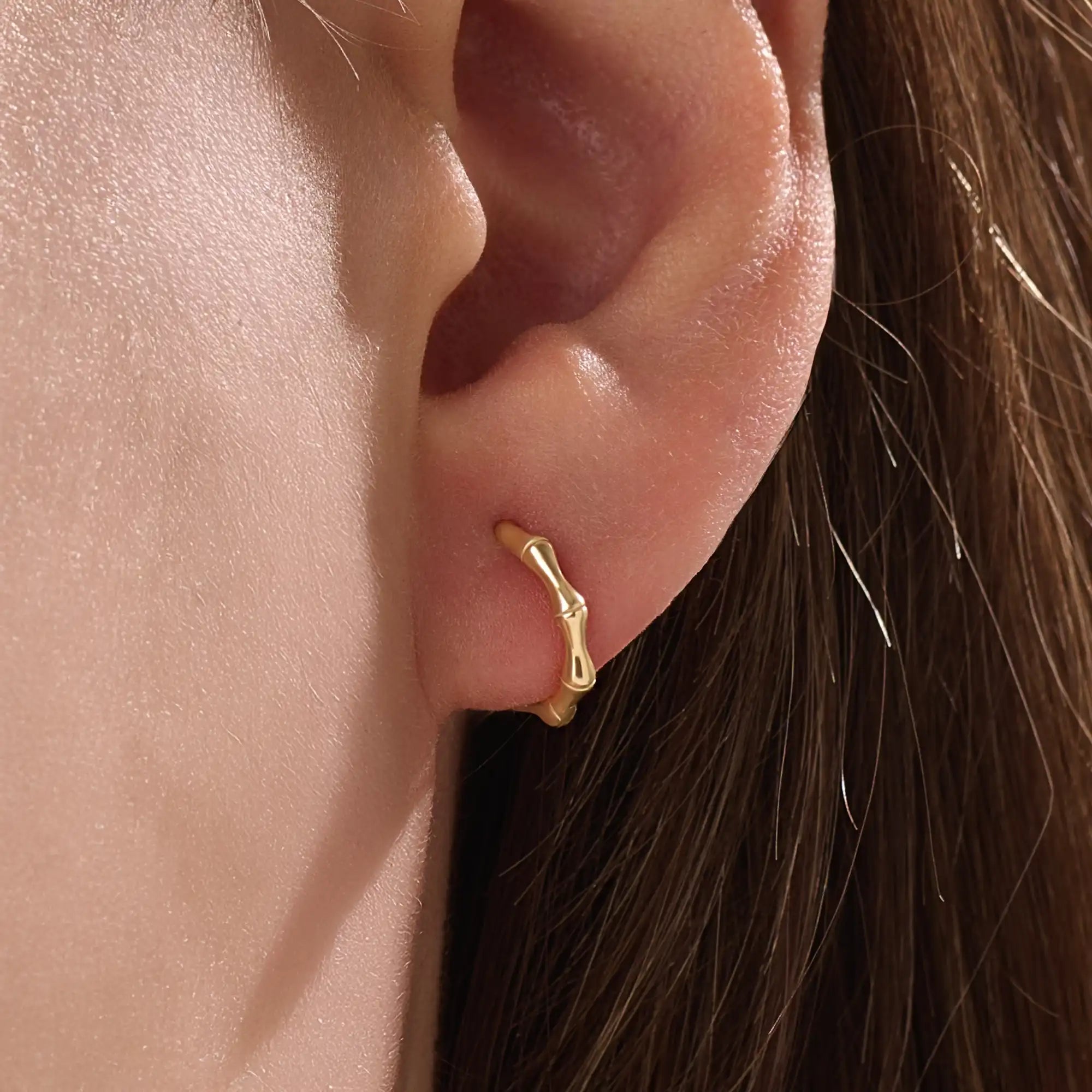 Model wearing 14k gold vermeil bone hoop earrings that highlight the sculpted, biomorphic design — a perfect mix of artistry and sophistication.
