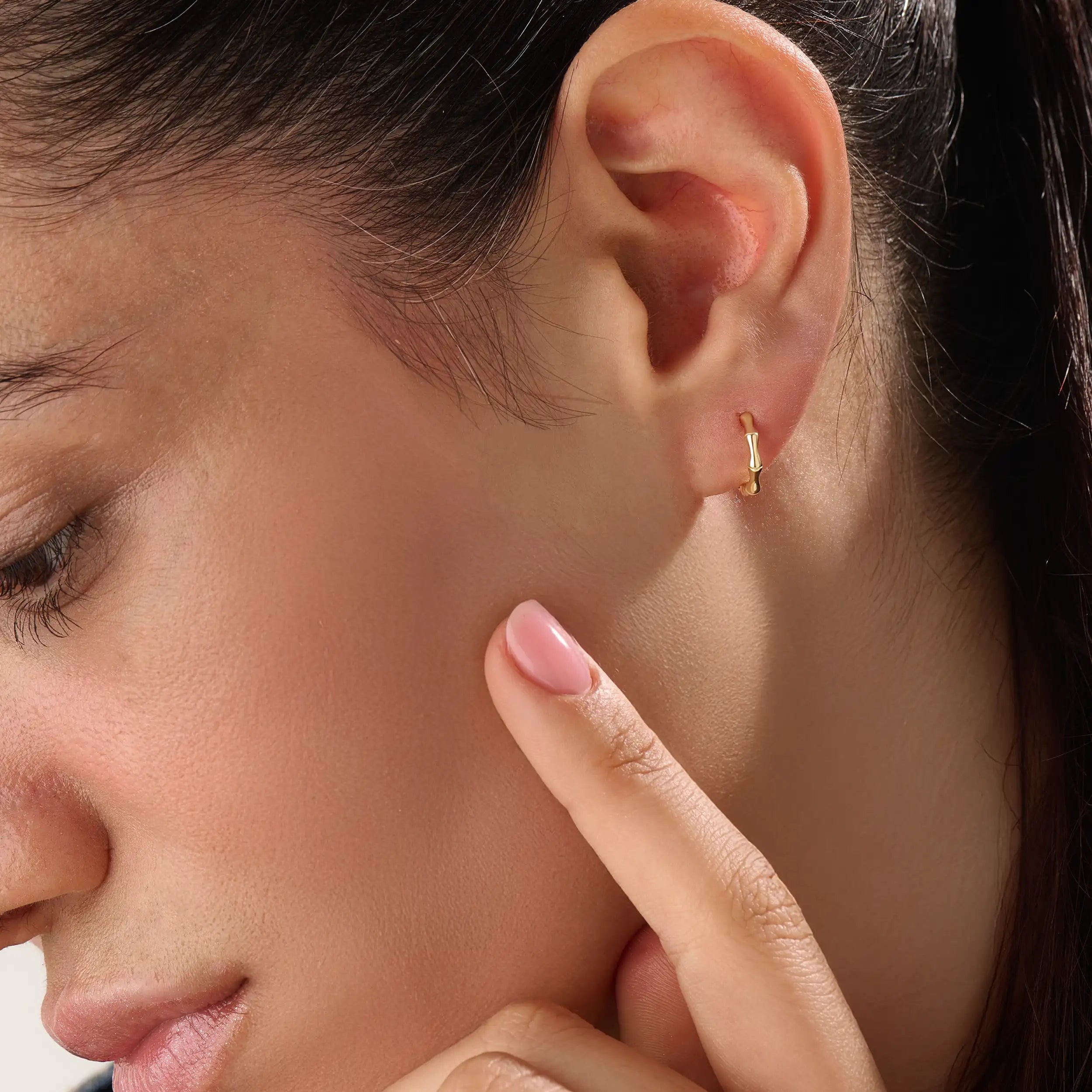 Model wearing 14k gold vermeil bone hoop earrings that highlight the sculpted, biomorphic design — a perfect mix of artistry and sophistication.

