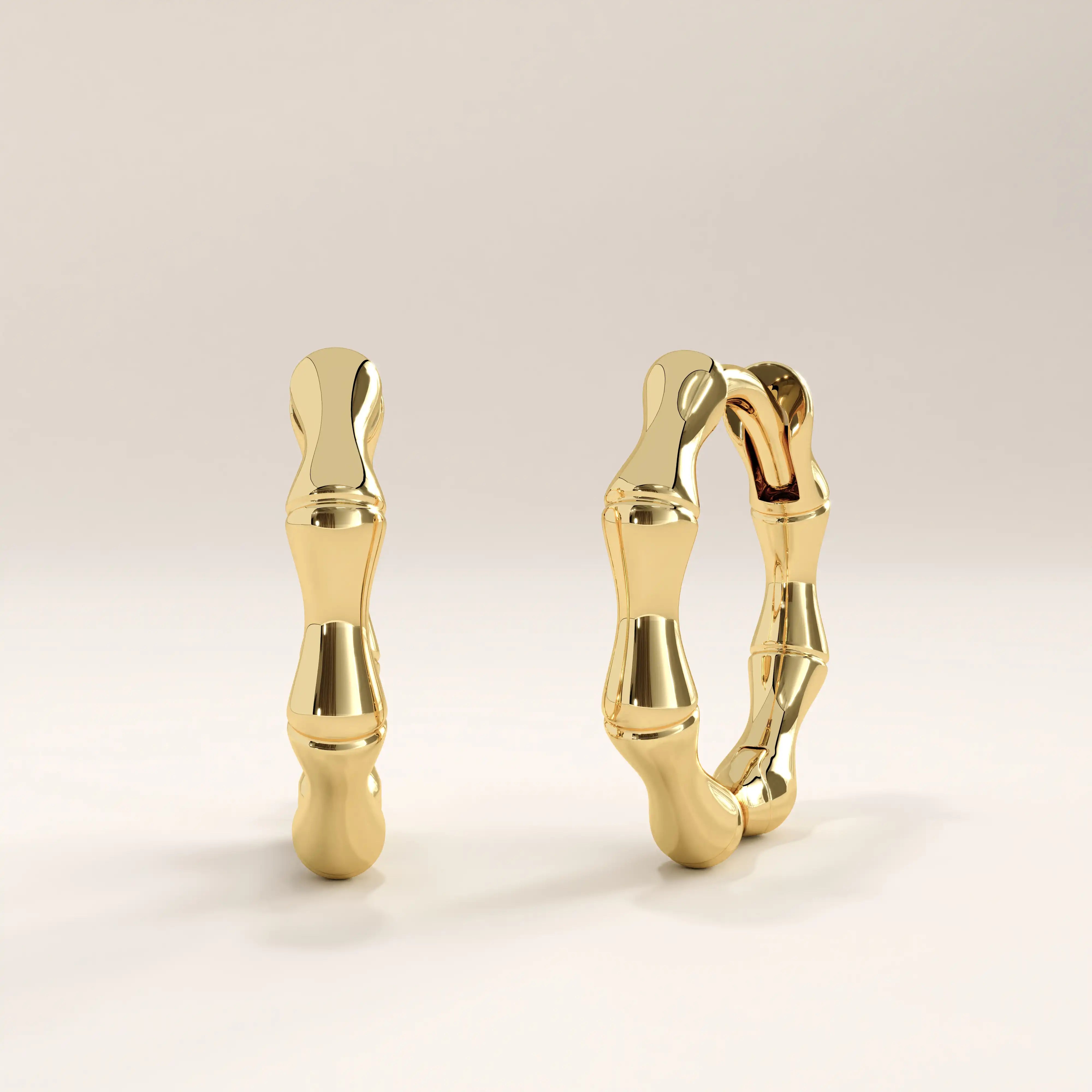Side view of 14k gold vermeil bone hoop earrings showcasing the irregular contours and smooth reflective surface for a statement natural aesthetic.

