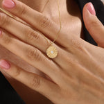 Model wearing a 14k gold vermeil coin necklace featuring a radiant engraved medallion pendant with a central cubic zirconia, adding a refined glow to any look.
