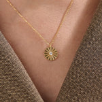 Model wearing a 14k gold vermeil coin necklace featuring a radiant engraved medallion pendant with a central cubic zirconia, adding a refined glow to any look.
