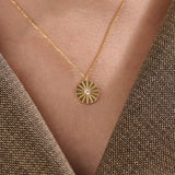 Model wearing a 14k gold vermeil coin necklace featuring a radiant engraved medallion pendant with a central cubic zirconia, adding a refined glow to any look.
