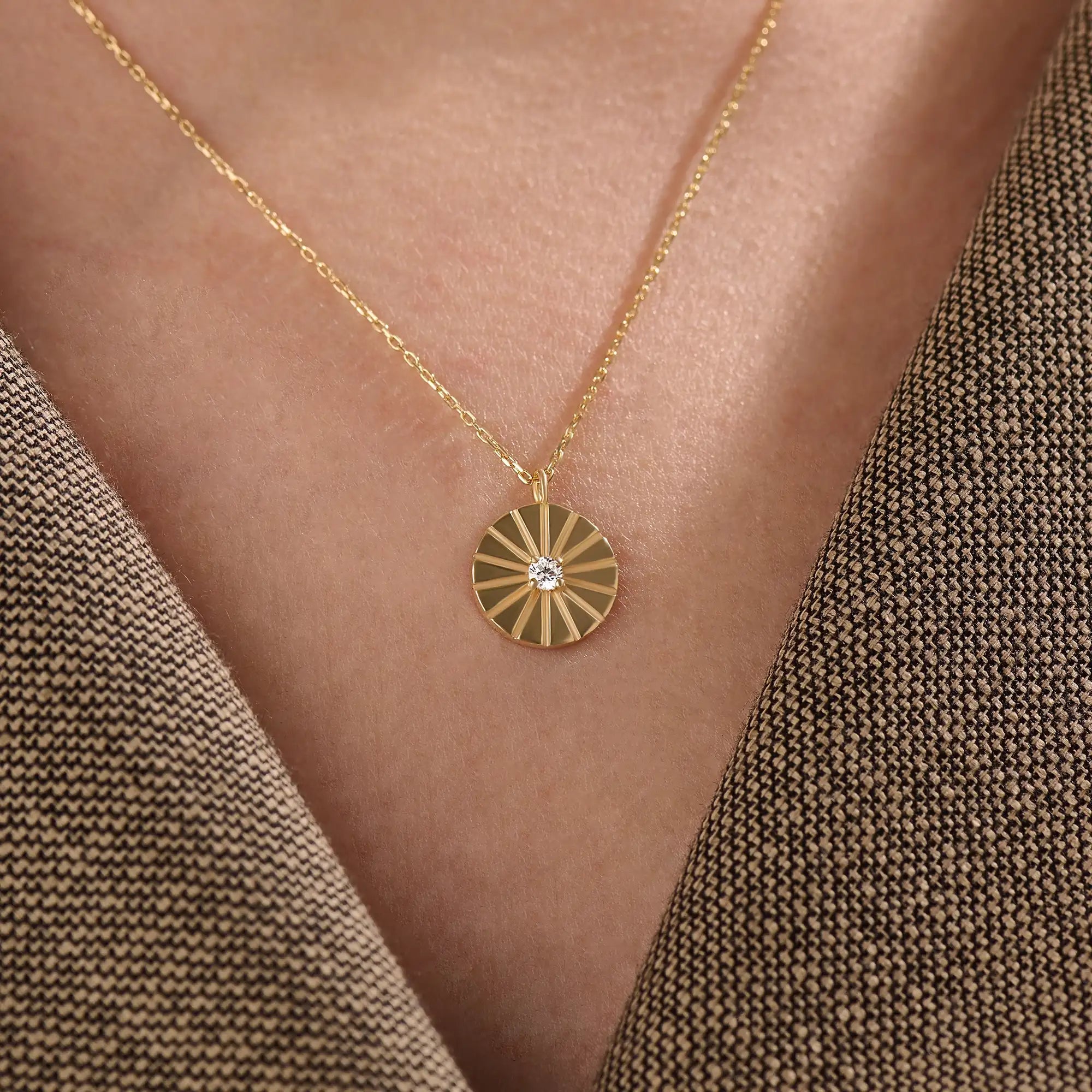 Model wearing a 14k gold vermeil coin necklace featuring a radiant engraved medallion pendant with a central cubic zirconia, adding a refined glow to any look.
