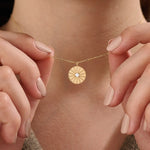 Model wearing a 14k gold vermeil coin necklace featuring a radiant engraved medallion pendant with a central cubic zirconia, adding a refined glow to any look.
