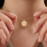 Model wearing a 14k gold vermeil coin necklace featuring a radiant engraved medallion pendant with a central cubic zirconia, adding a refined glow to any look.
