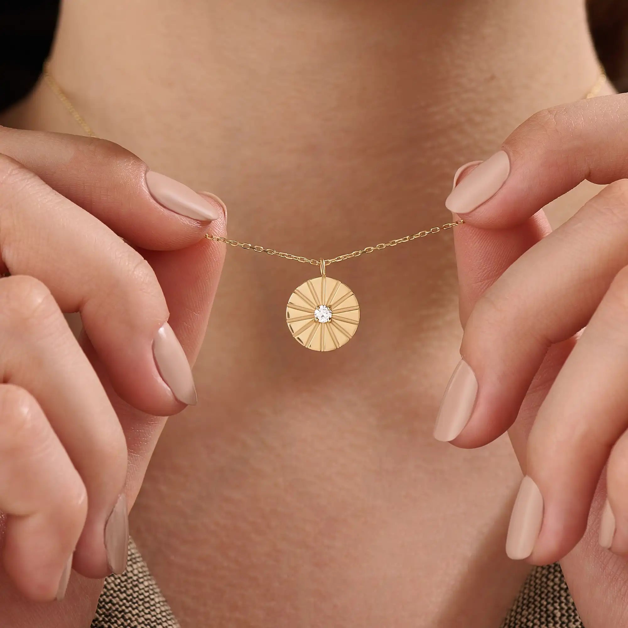 Model wearing a 14k gold vermeil coin necklace featuring a radiant engraved medallion pendant with a central cubic zirconia, adding a refined glow to any look.
