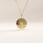 Side view of 14k gold vermeil coin necklace highlighting the raised sunburst pattern and bezel-set cubic zirconia at the center of the pendant.
