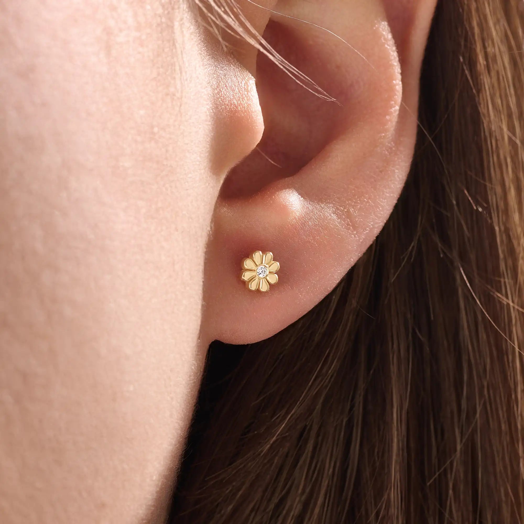 Model wearing 14k gold vermeil daisy stud earrings featuring a floral silhouette and shimmering cubic zirconia center, perfect for an elegant, nature-inspired look.
