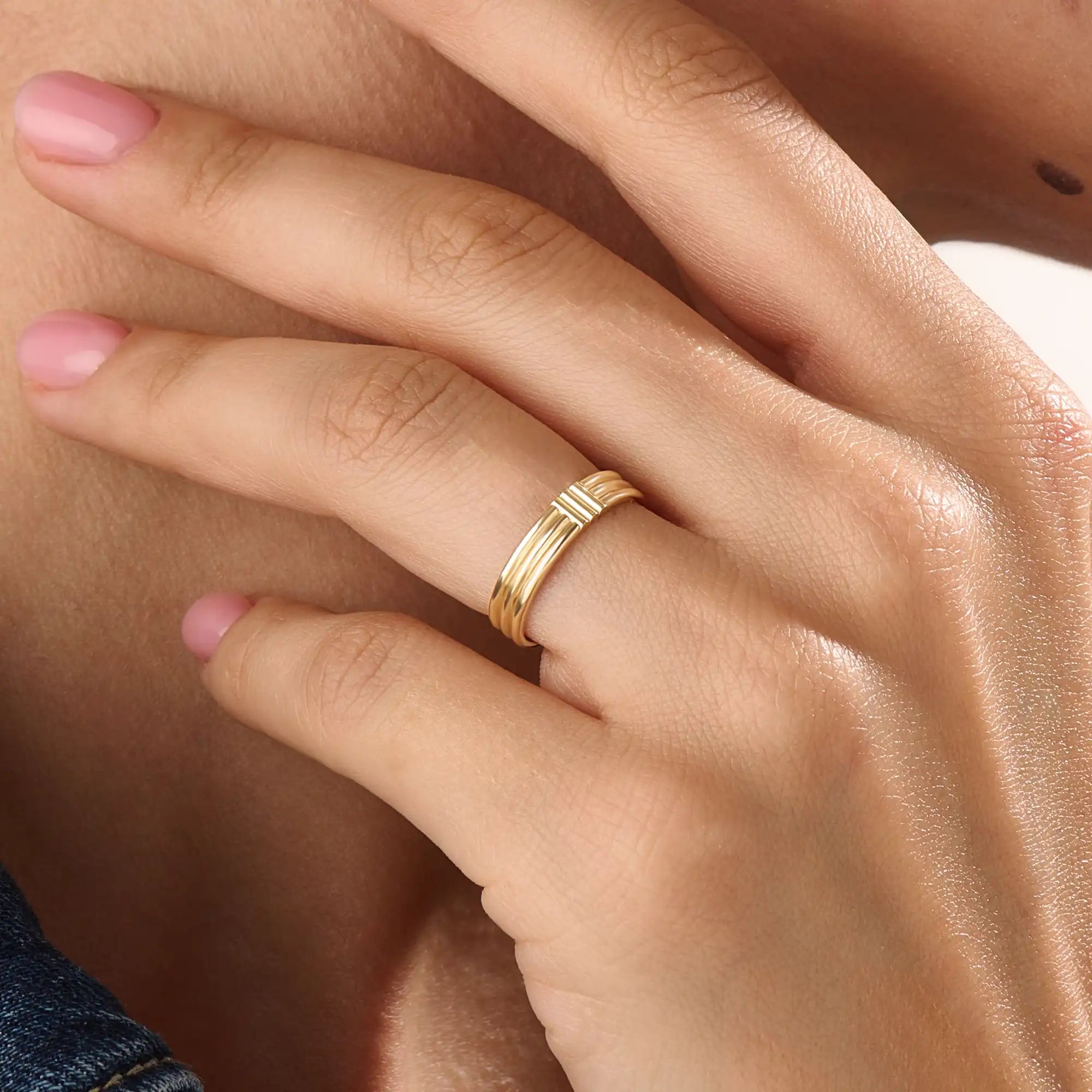 Model wearing a 14k gold vermeil line band ring, showcasing its elegant triple-line design and lustrous golden finish for a timeless minimalist look.
