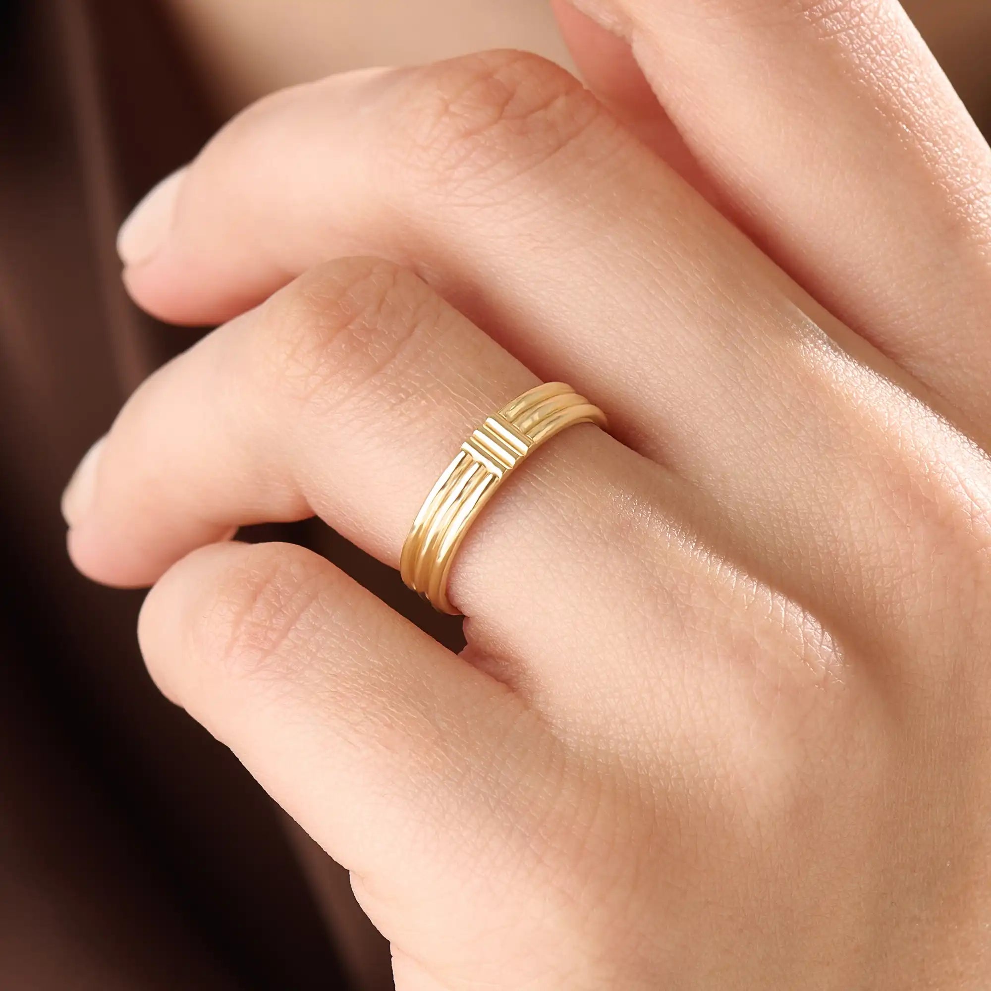 Model wearing a 14k gold vermeil line band ring, showcasing its elegant triple-line design and lustrous golden finish for a timeless minimalist look.
