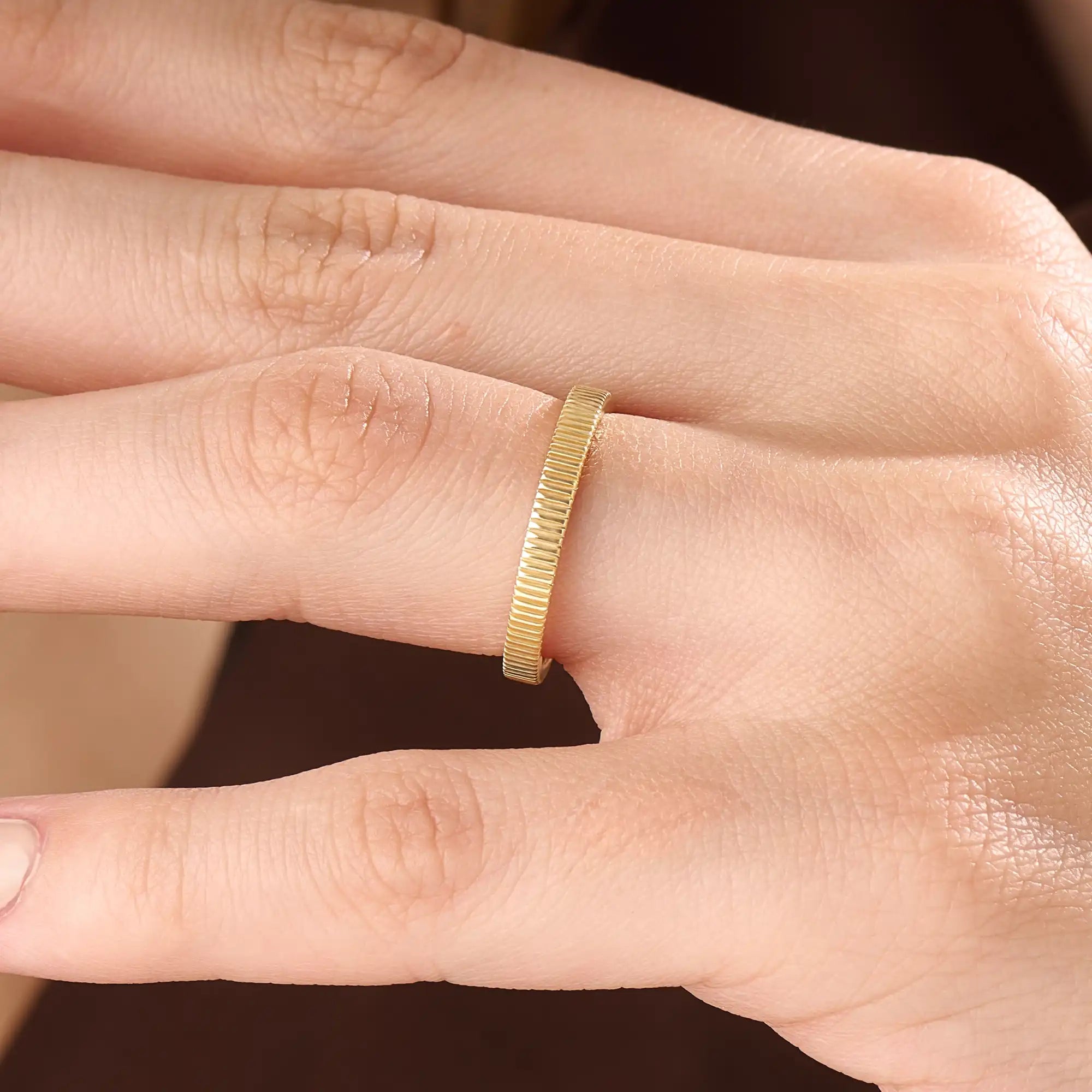 Model wearing a 14k gold vermeil lined band ring, emphasizing its modern ribbed texture and elegant golden tone for a timeless everyday look.
