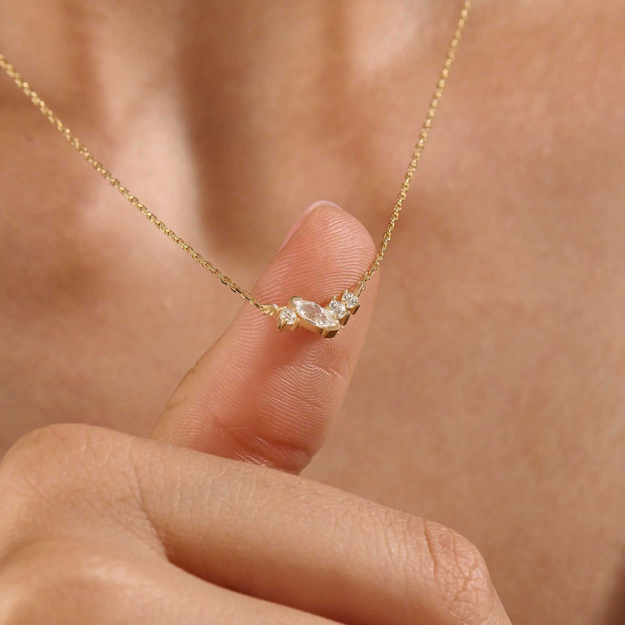 Model wearing a 14k gold vermeil mixed cut necklace featuring a cluster of marquise and round cubic zirconia stones, radiating delicate elegance and everyday glamour.
