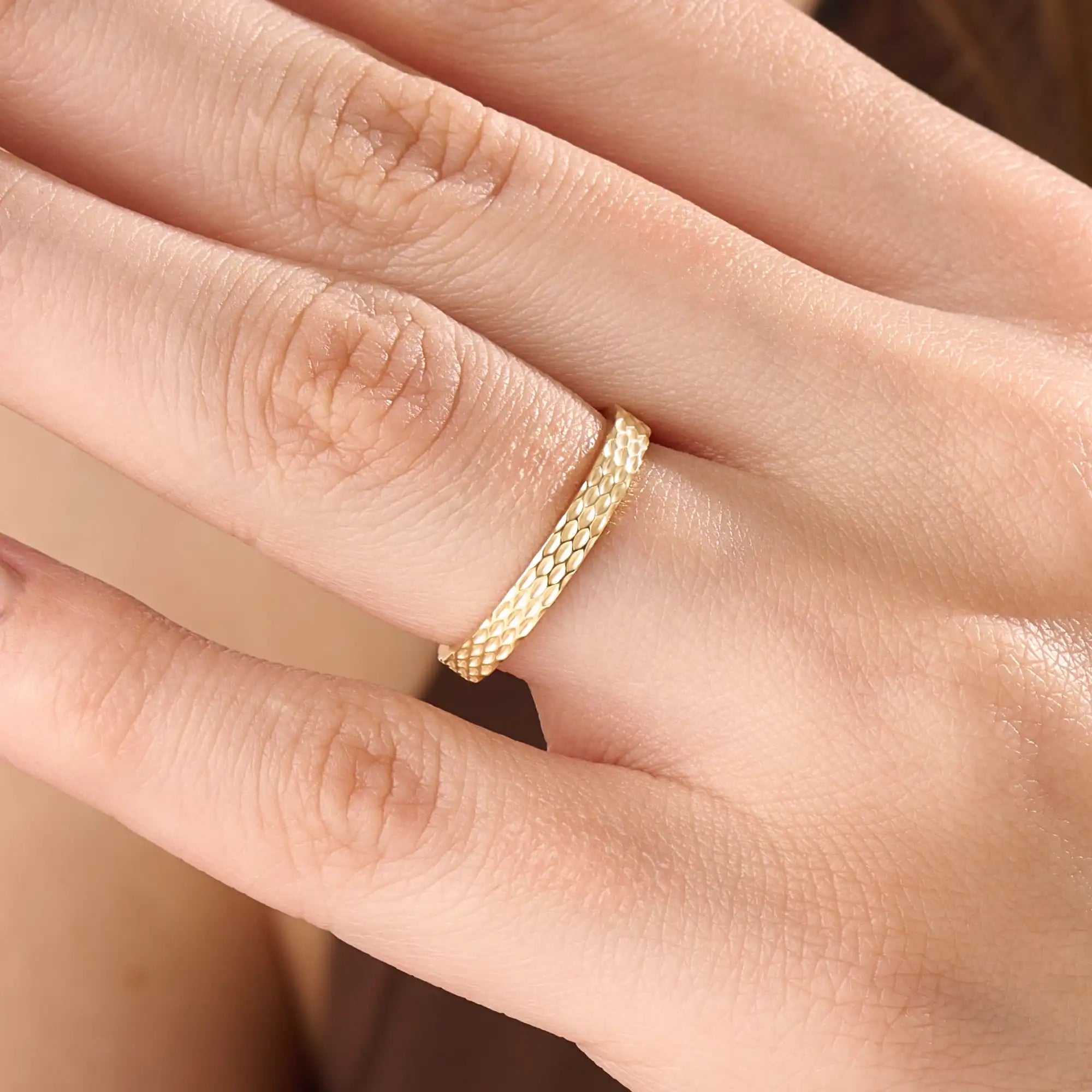 Model wearing a 14k gold vermeil patterned band ring with a shimmering diamond-like texture, reflecting light beautifully for a chic statement look.
