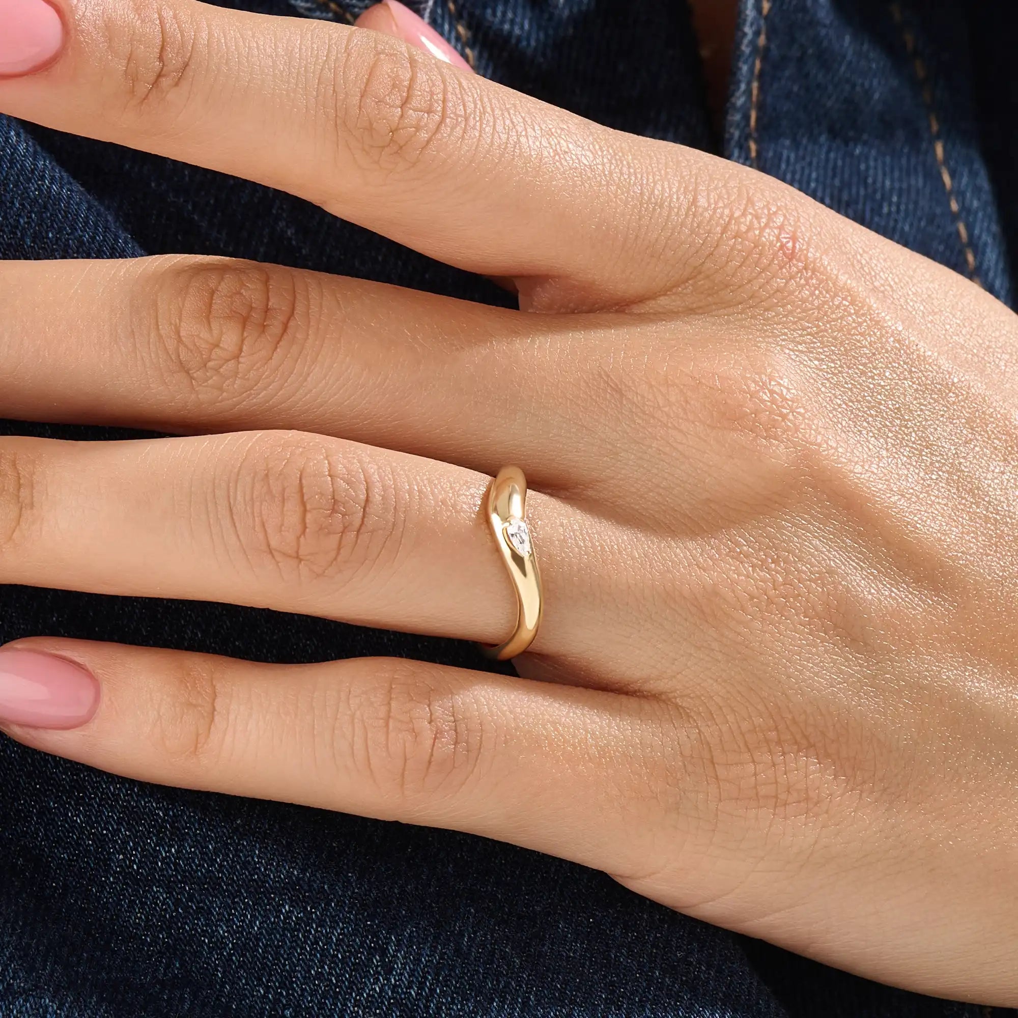 Model wearing a 14k gold vermeil pear curve ring with an elegant sweeping design and a single pear-cut stone for a graceful, luminous finish.
