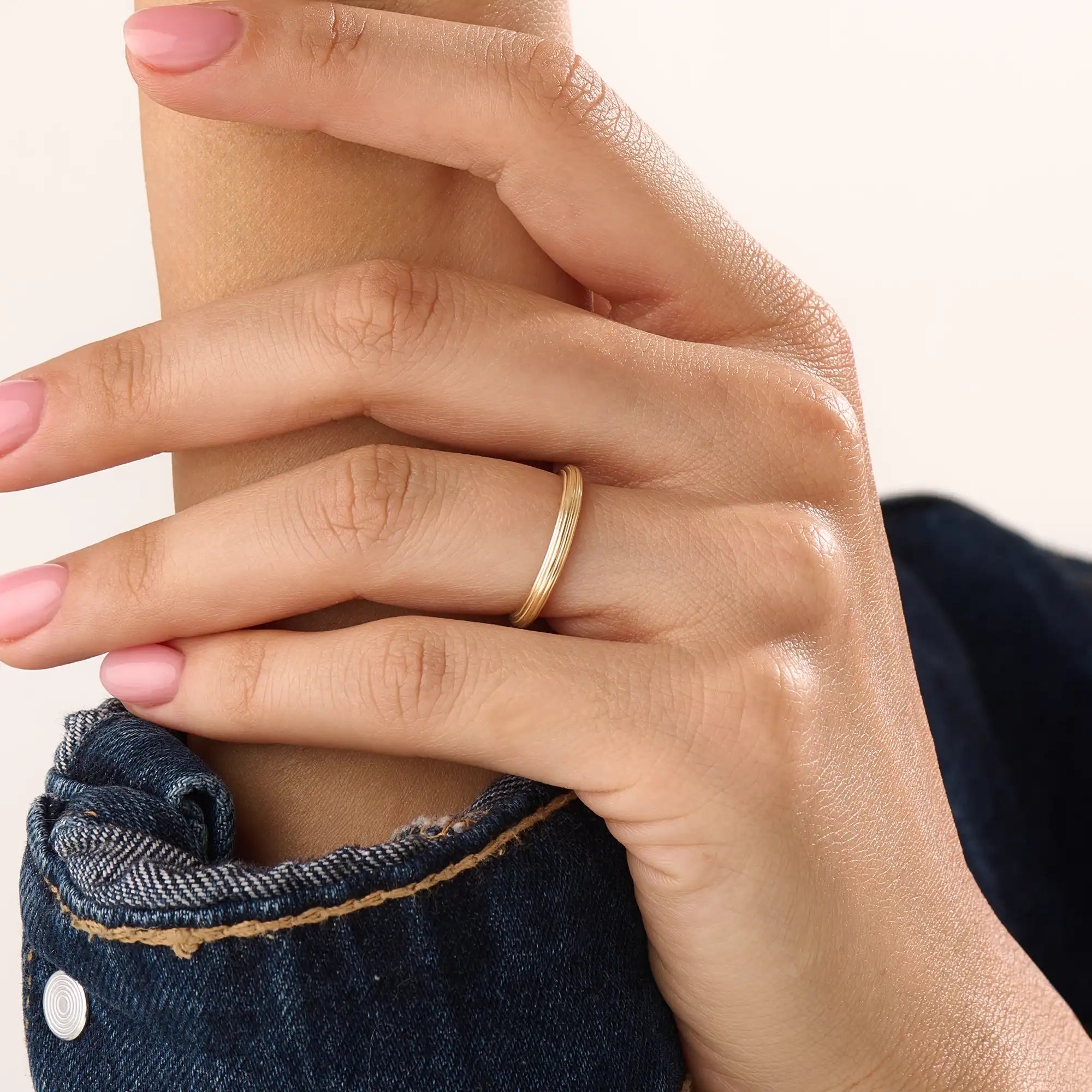 Model wearing a 14k gold vermeil simple band ring, highlighting its slim layered design and radiant gold sheen for a refined modern look.
