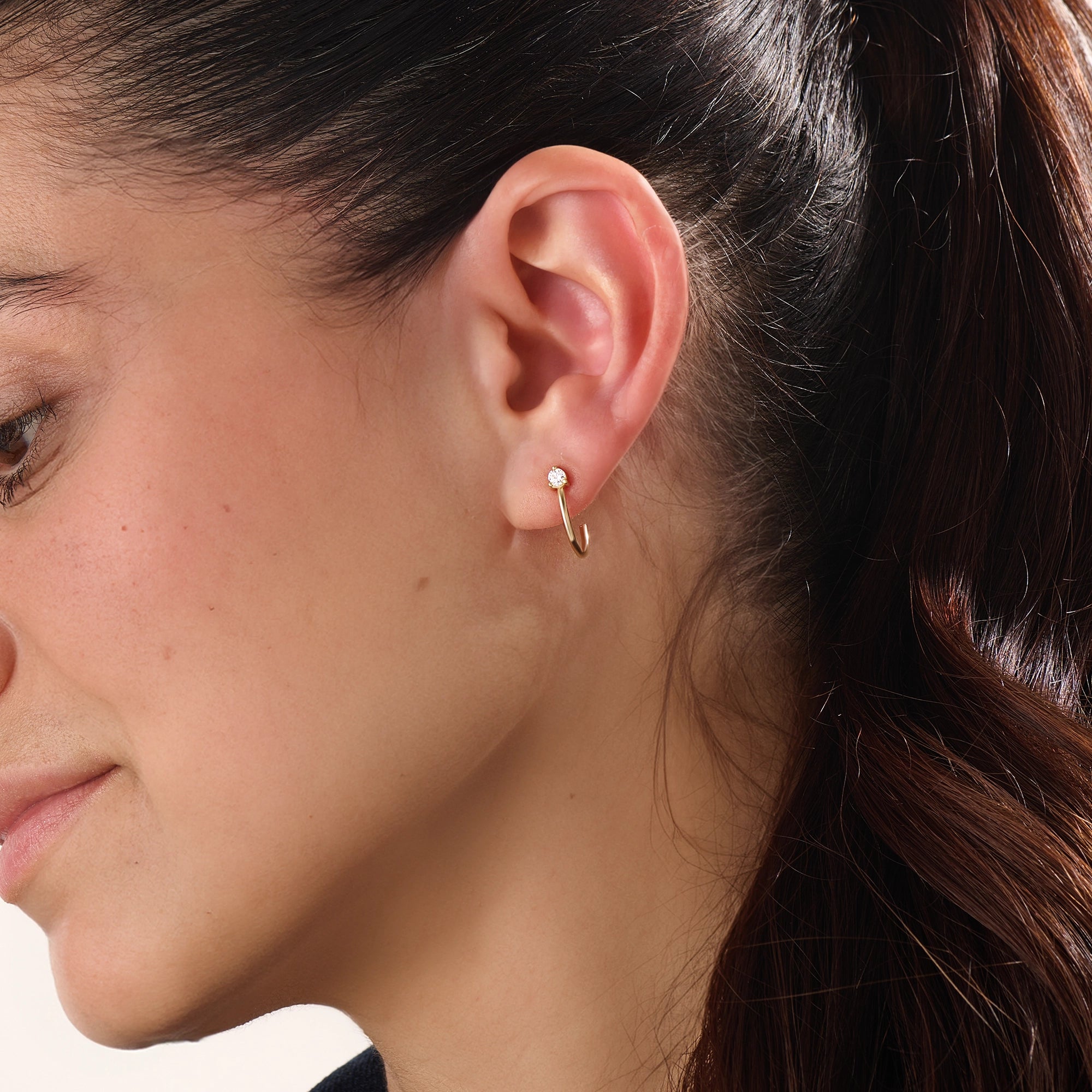 Model wearing 14k gold vermeil solo hoop earrings showcasing a single sparkling cubic zirconia, perfect for an understated yet sophisticated everyday look.
