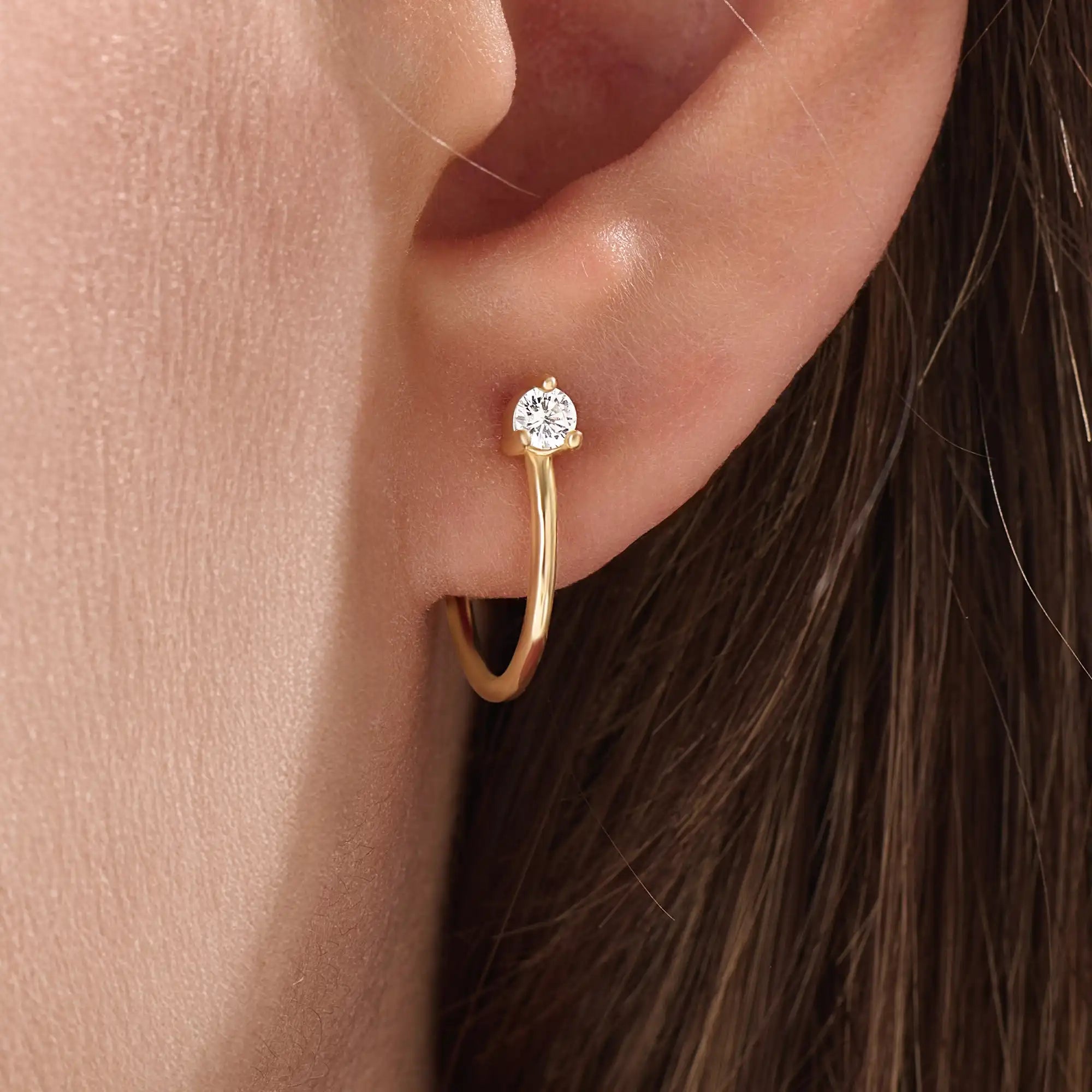Model wearing 14k gold vermeil solo hoop earrings showcasing a single sparkling cubic zirconia, perfect for an understated yet sophisticated everyday look.
