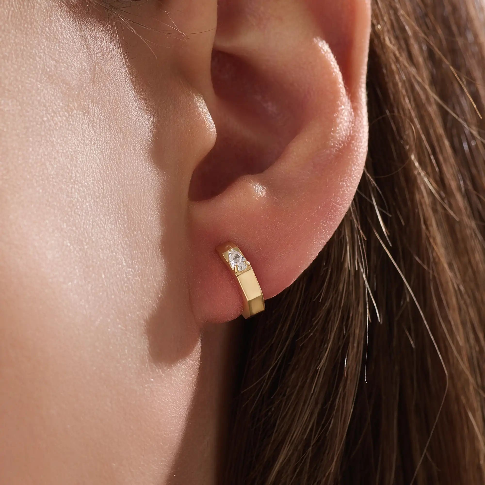 Model wearing 14k gold vermeil solo pear hoop earrings displaying the striking pear-cut gem and sculpted gold finish — perfect for elegant minimalism.
