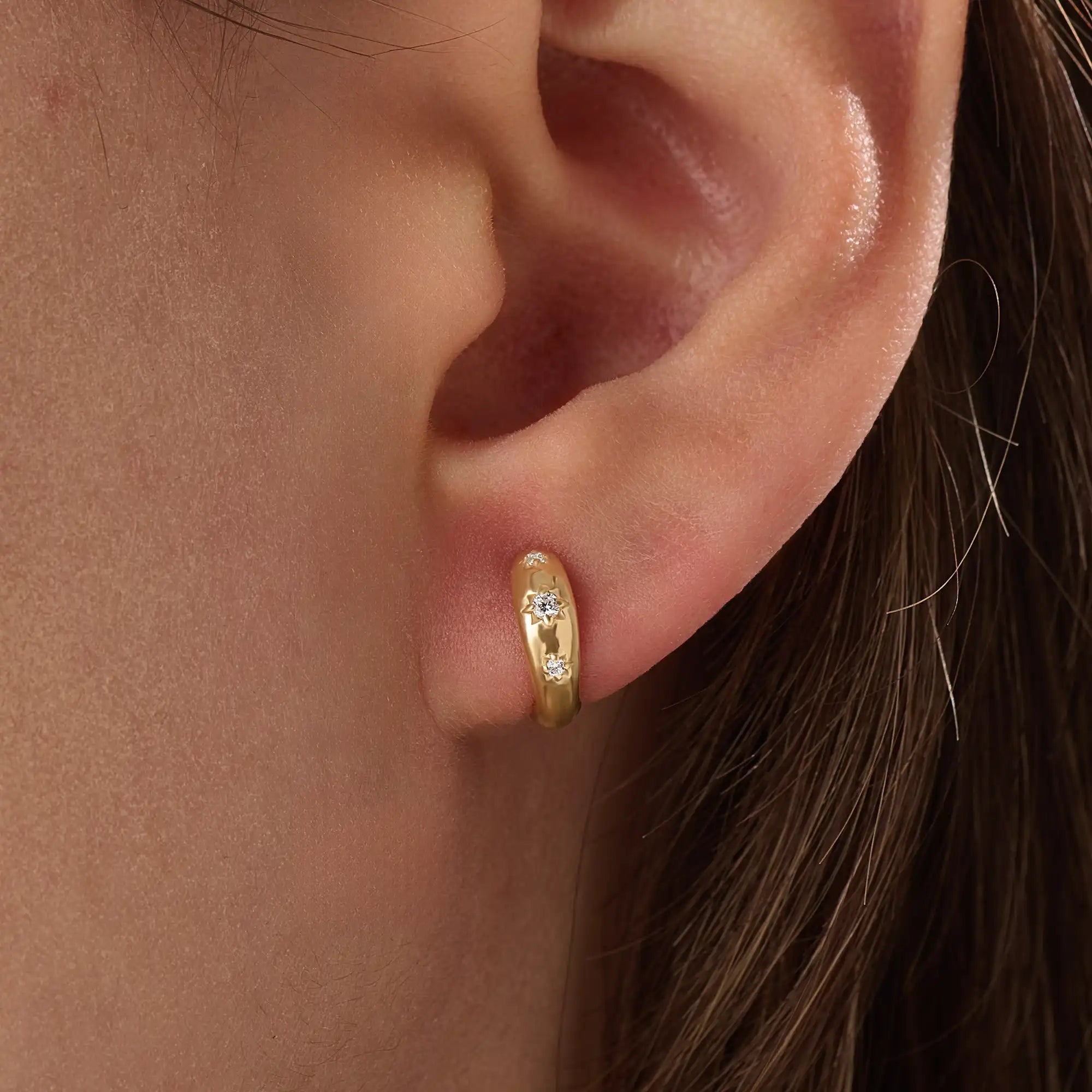 Model wearing 14k gold vermeil star hoop earrings showcasing a luminous gold finish and twinkling stone details, perfect for adding celestial elegance to any outfit.
